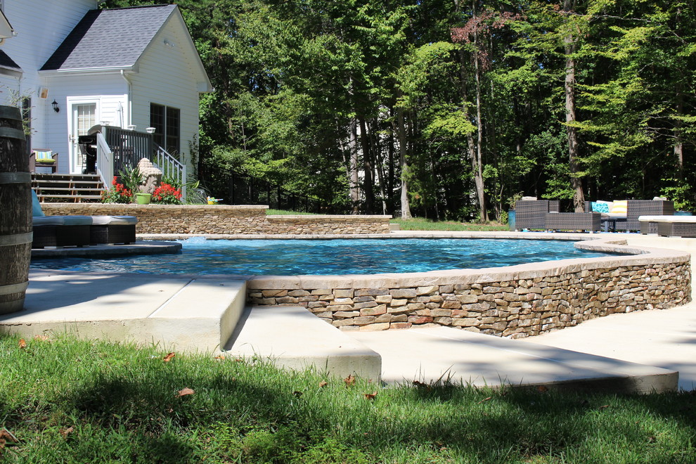 Ejemplo de piscina natural rural de tamaño medio a medida en patio delantero con losas de hormigón