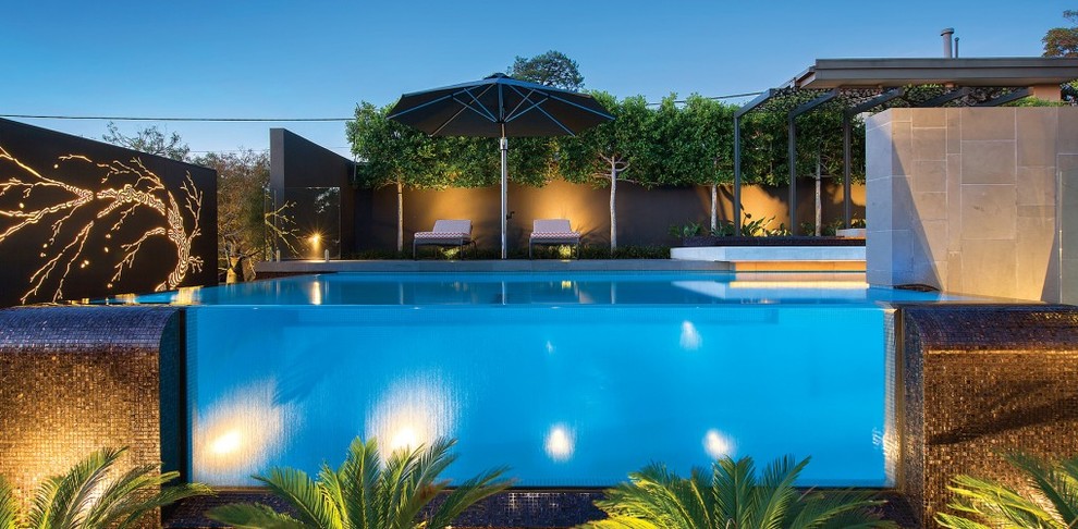 Foto di una grande piscina monocorsia moderna rettangolare dietro casa con fontane e piastrelle