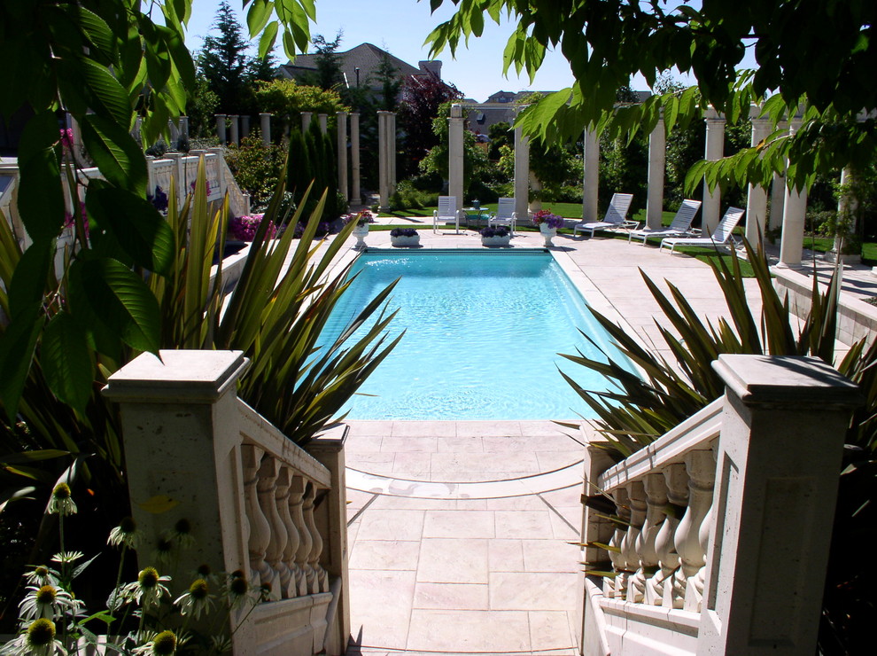 Ejemplo de piscina mediterránea rectangular en patio trasero con adoquines de hormigón