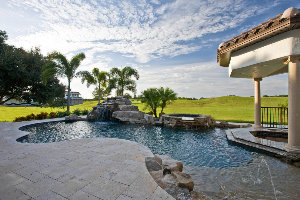 Foto de piscina con fuente alargada tropical de tamaño medio en patio trasero con adoquines de piedra natural
