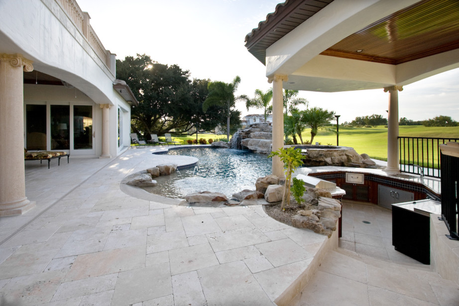 Imagen de piscina exótica grande a medida en patio trasero con adoquines de piedra natural