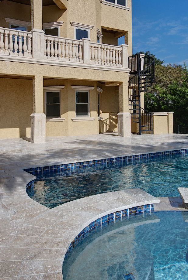 Modelo de piscina alargada mediterránea rectangular en patio trasero con adoquines de piedra natural