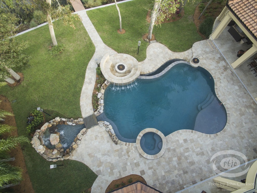 Modelo de piscina infinita tropical grande a medida en patio trasero con adoquines de piedra natural