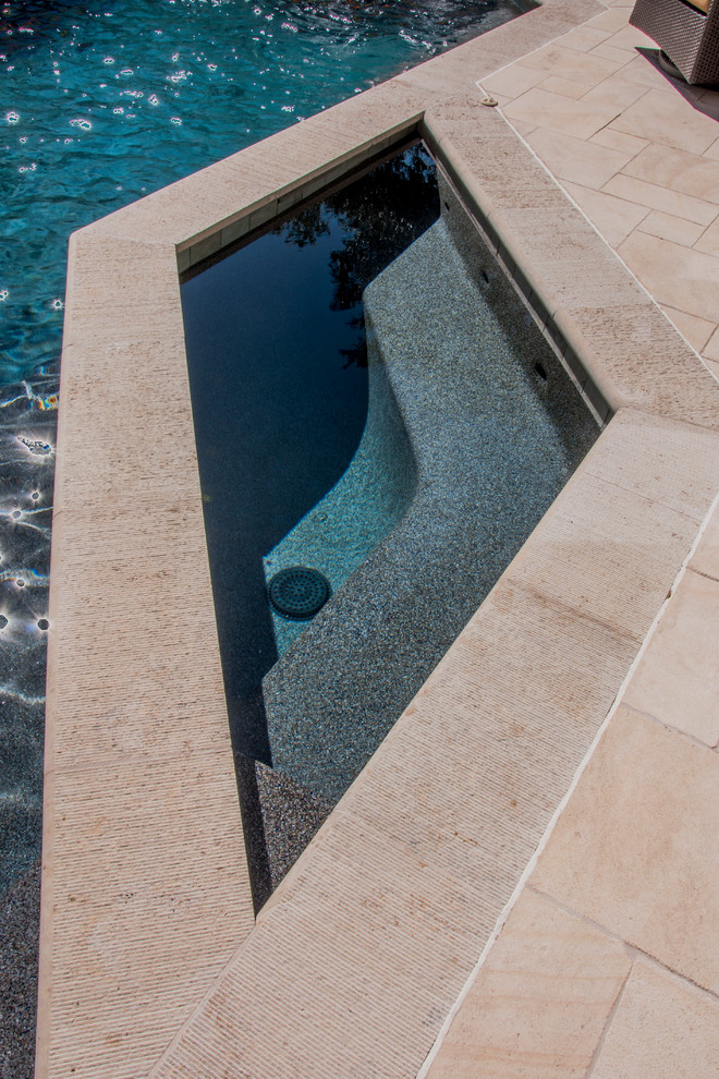 Réalisation d'une petite piscine naturelle et arrière méditerranéenne sur mesure avec un bain bouillonnant et des pavés en pierre naturelle.