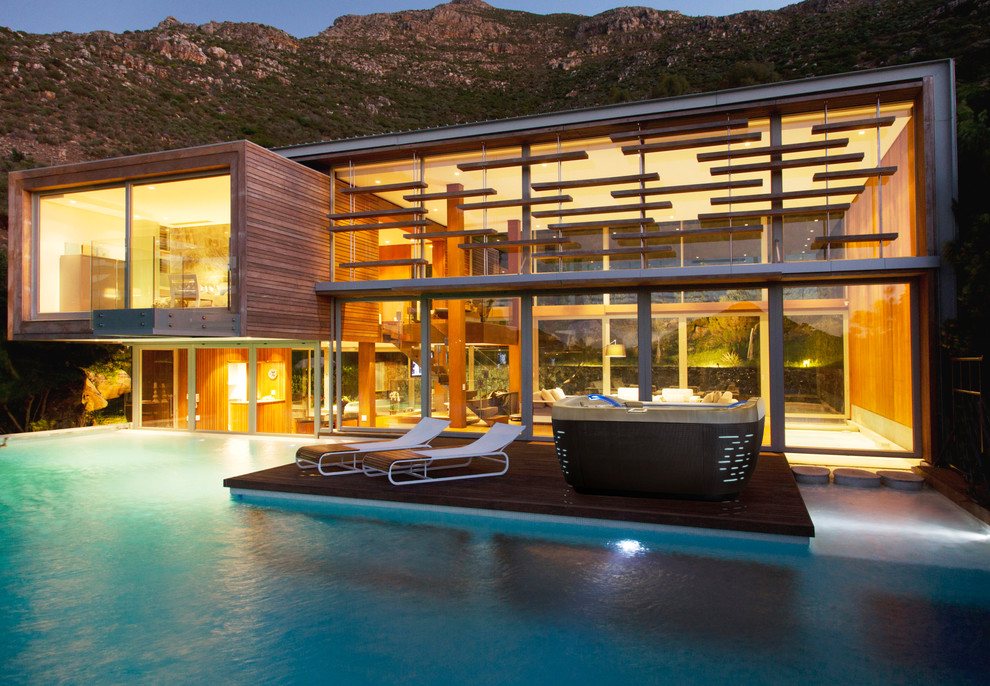 Ispirazione per un'ampia piscina naturale minimalista personalizzata dietro casa con una vasca idromassaggio e pedane