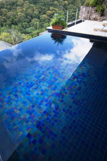 Esempio di un'ampia piscina a sfioro infinito tropicale personalizzata sul tetto con fontane e piastrelle