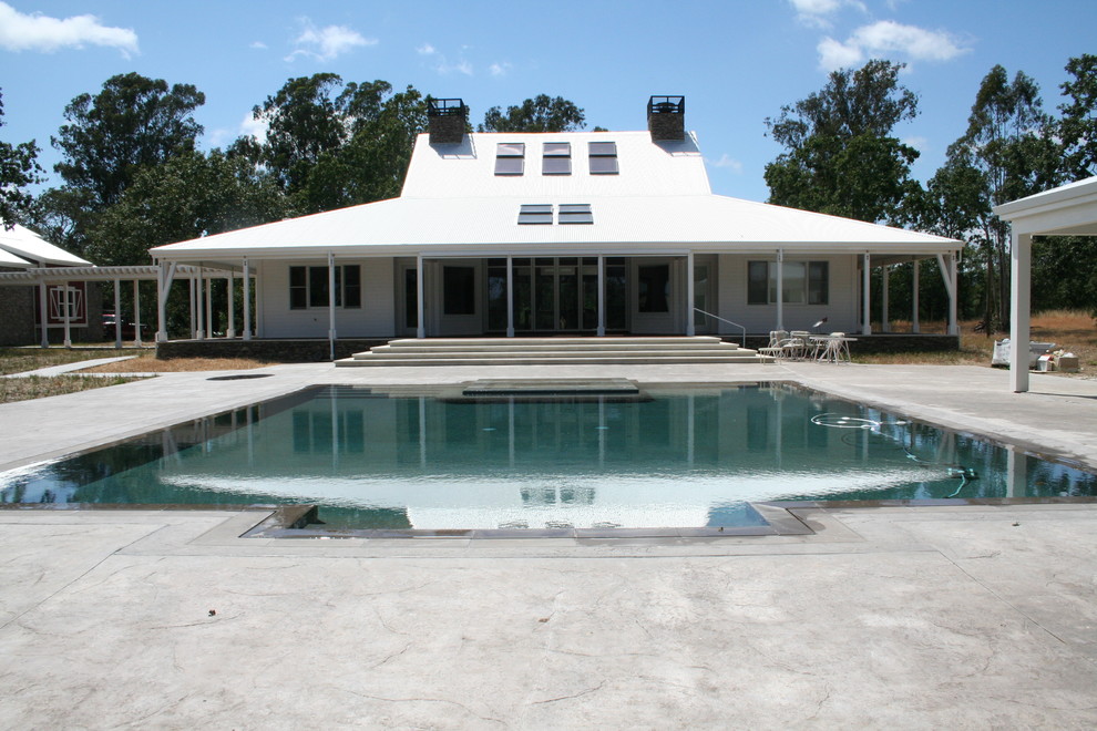 Diseño de piscinas y jacuzzis infinitos actuales de tamaño medio rectangulares en patio trasero con suelo de hormigón estampado