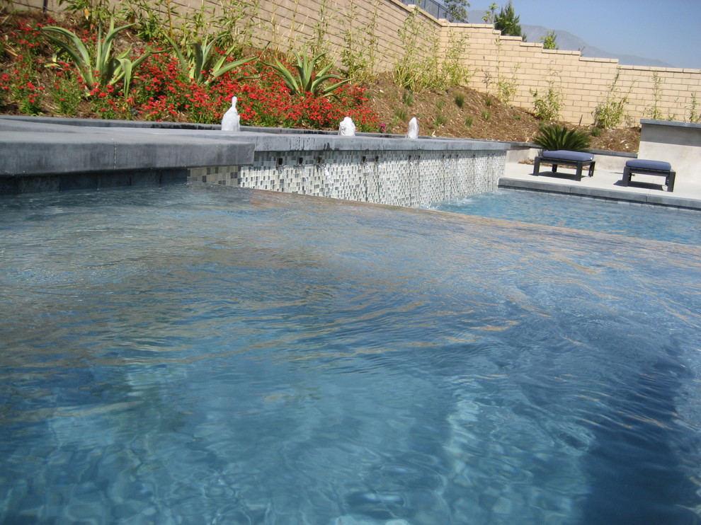 Mittelgroßer, Oberirdischer Asiatischer Pool hinter dem Haus in rechteckiger Form mit Wasserspiel und Betonplatten in Orange County