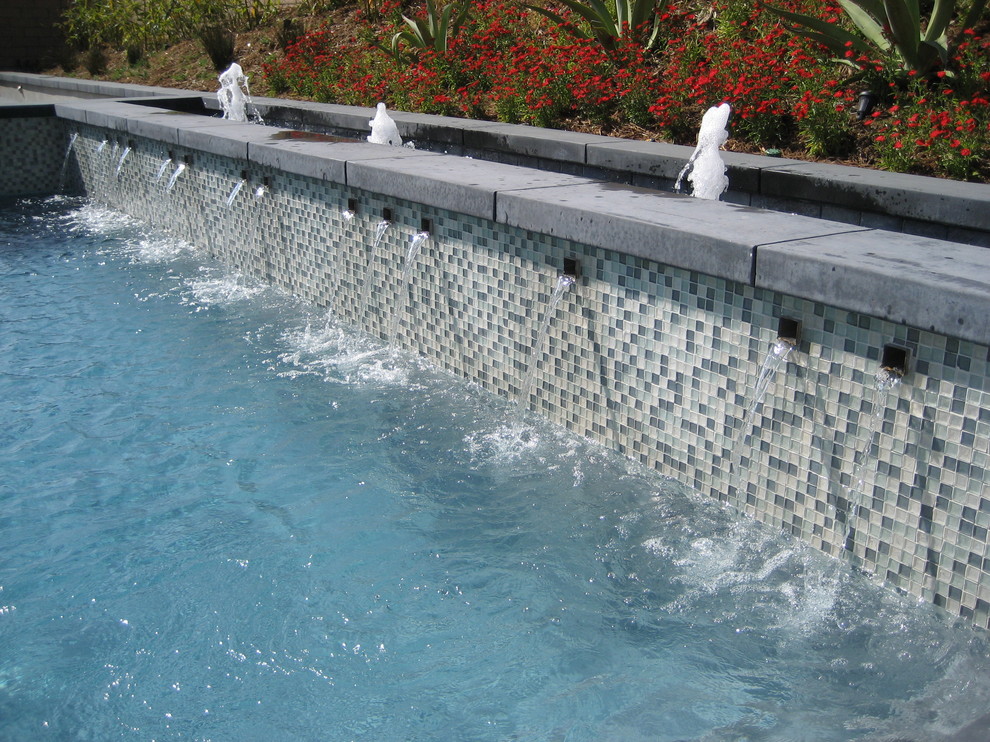 Foto di una piscina naturale etnica rettangolare di medie dimensioni e dietro casa con fontane e lastre di cemento