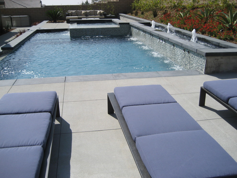 Diseño de piscinas y jacuzzis elevados de estilo zen de tamaño medio a medida en patio trasero con losas de hormigón