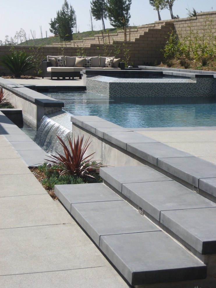 На фото: наземный бассейн среднего размера, произвольной формы на заднем дворе в восточном стиле с джакузи и покрытием из бетонных плит
