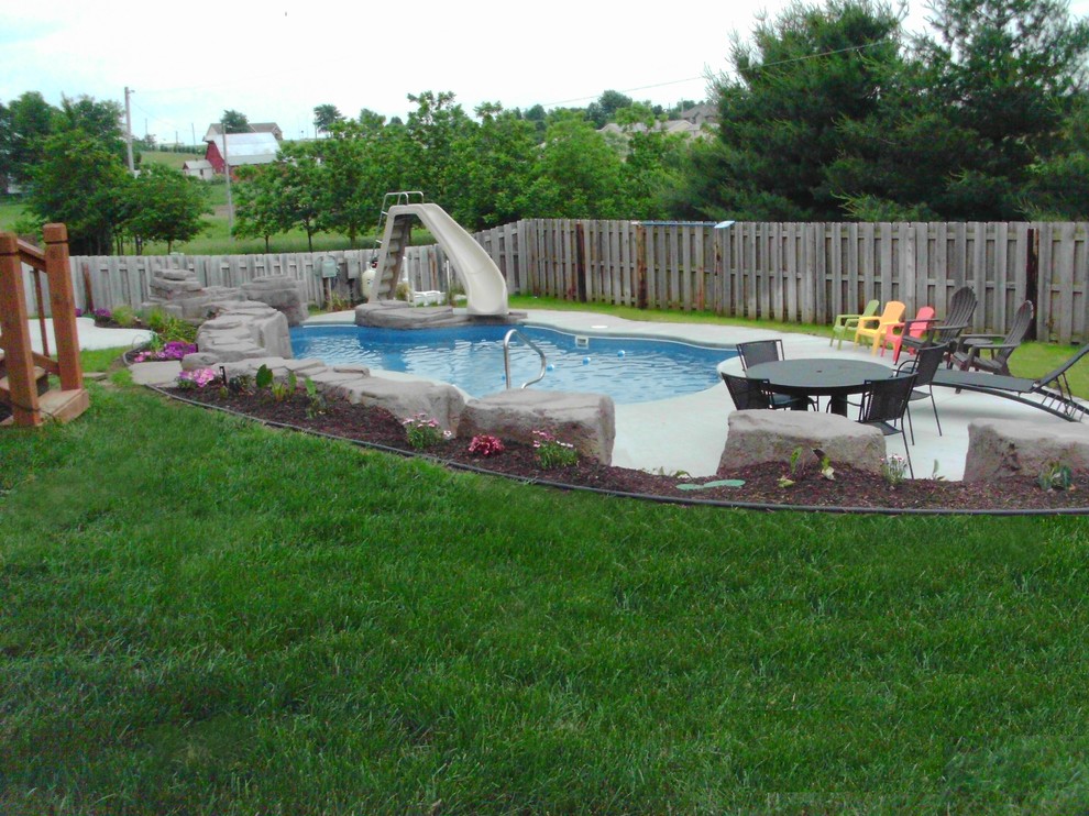 Стильный дизайн: большой естественный бассейн произвольной формы на заднем дворе в стиле рустика с водной горкой и покрытием из декоративного бетона - последний тренд