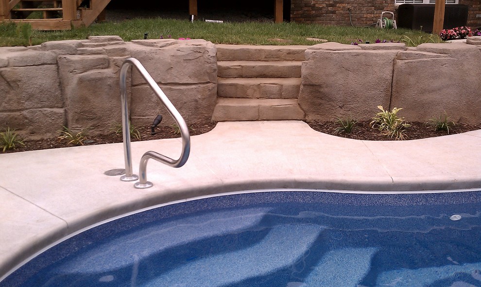На фото: большой естественный бассейн произвольной формы на заднем дворе в стиле рустика с водной горкой и покрытием из декоративного бетона с