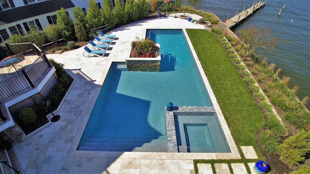 Ispirazione per una grande piscina design a "L" dietro casa con pavimentazioni in pietra naturale