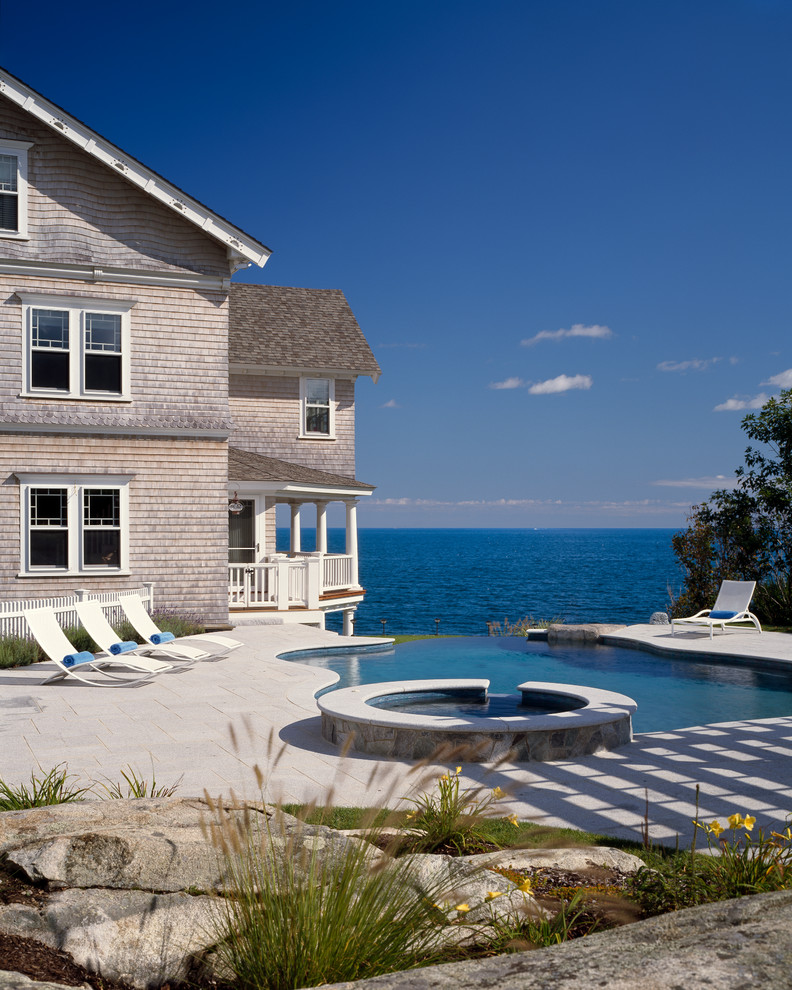 Large ornate side yard stone and custom-shaped infinity hot tub photo in Boston