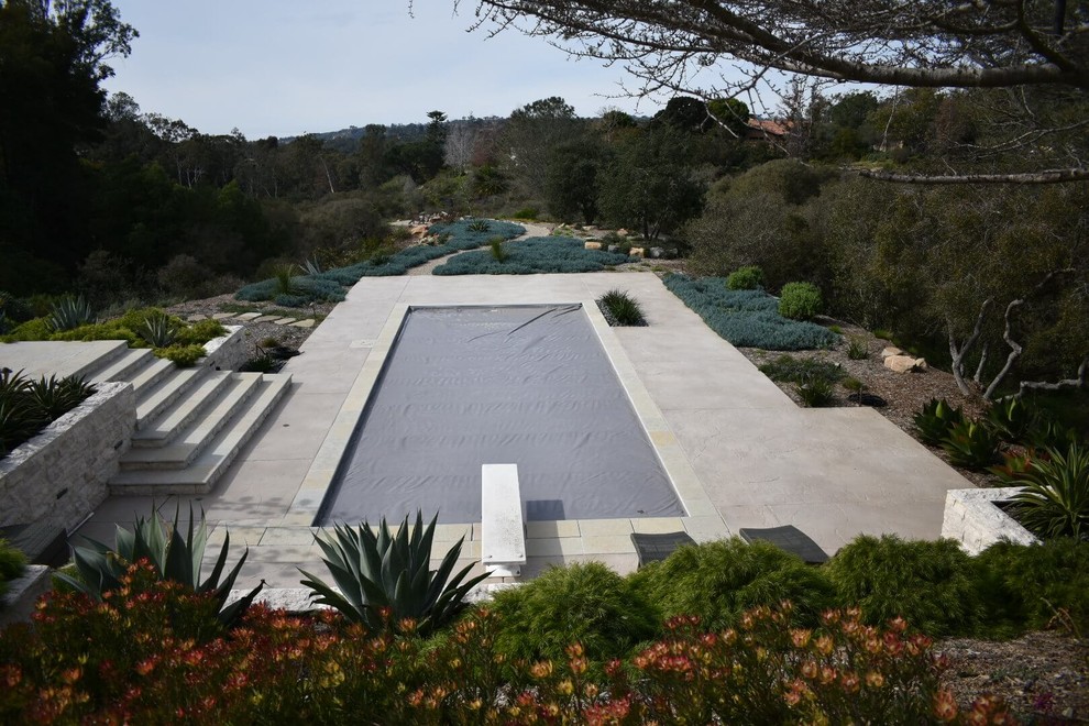Modelo de piscina alargada mediterránea pequeña rectangular en patio trasero con losas de hormigón