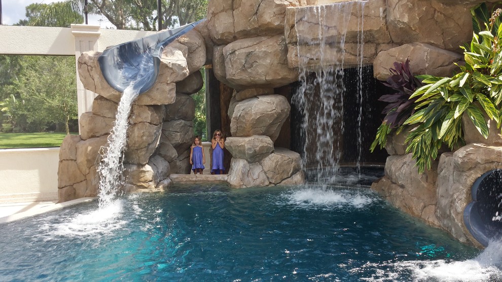 Immagine di una grande piscina monocorsia design dietro casa con un acquascivolo