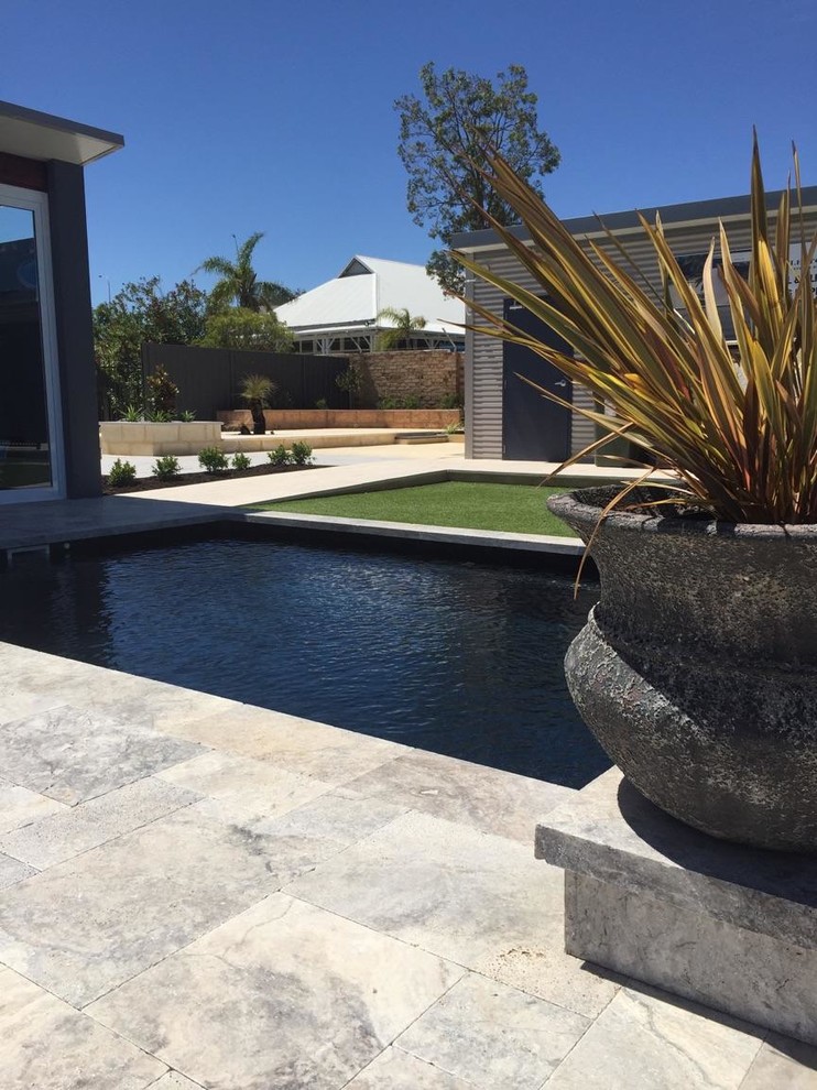 Imagen de piscina alargada contemporánea de tamaño medio rectangular con adoquines de piedra natural