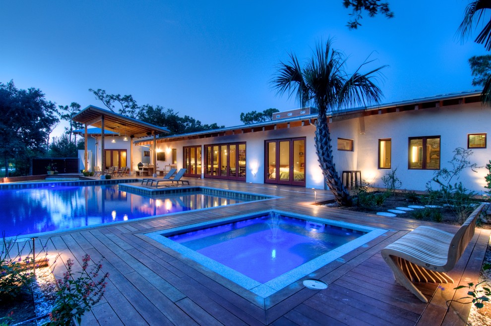 Idee per una grande piscina monocorsia minimalista personalizzata dietro casa con pedane e una vasca idromassaggio
