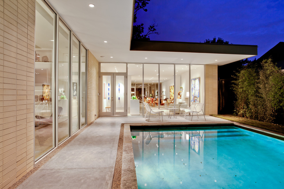 Design ideas for a medium sized midcentury courtyard rectangular swimming pool in Dallas with concrete slabs.