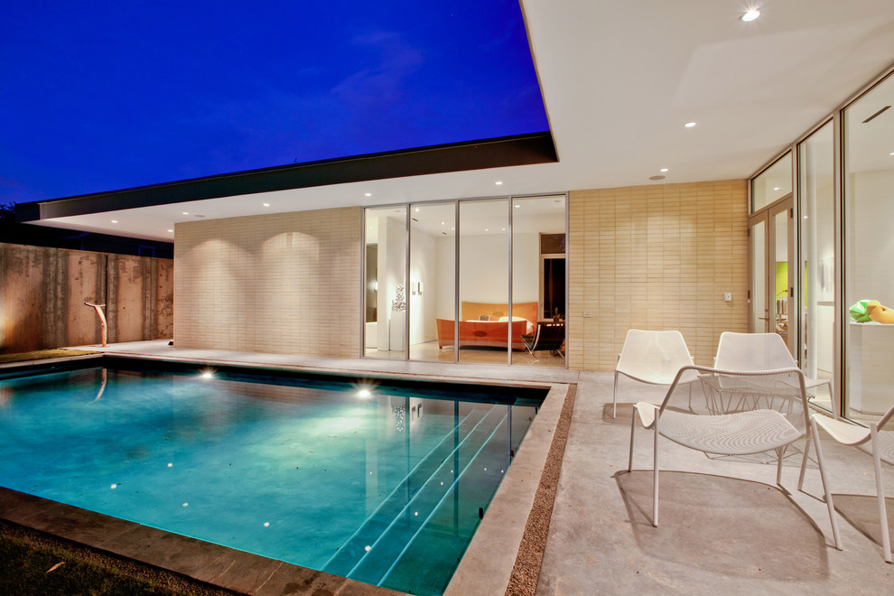 Exemple d'une piscine moderne de taille moyenne et rectangle avec une cour et une dalle de béton.