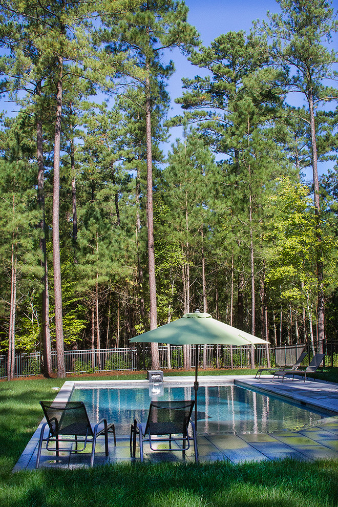 Modelo de piscina con fuente alargada contemporánea de tamaño medio a medida en patio trasero con adoquines de hormigón