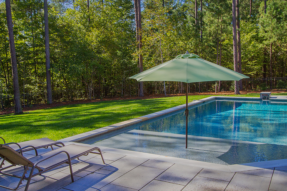 Diseño de piscina con fuente alargada actual de tamaño medio a medida en patio trasero con adoquines de hormigón