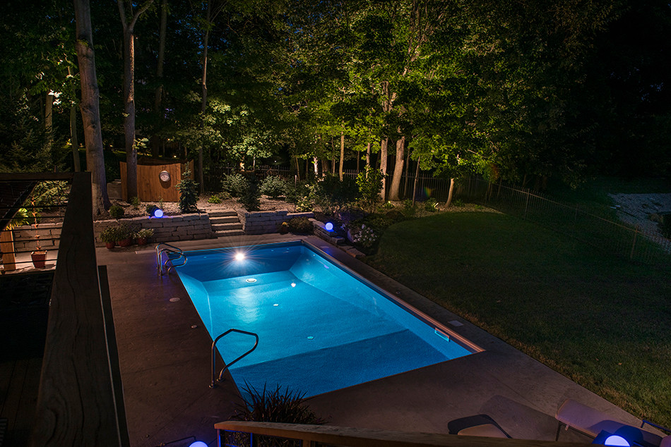 Ejemplo de piscina alargada actual grande rectangular en patio trasero con losas de hormigón