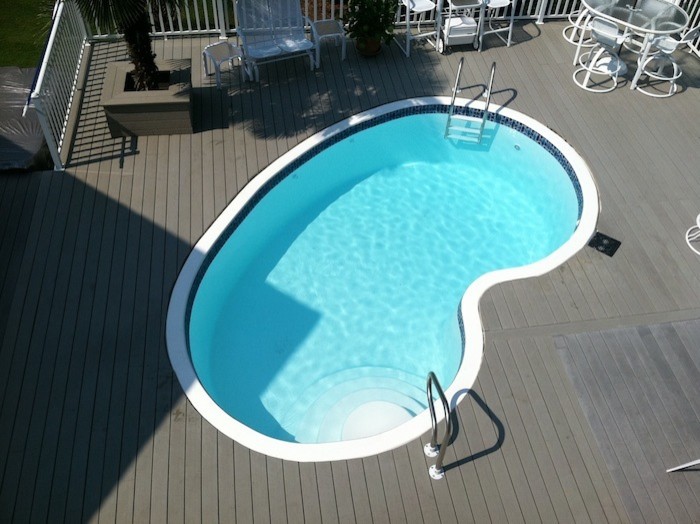 Foto de piscina tradicional de tamaño medio tipo riñón en patio trasero con entablado