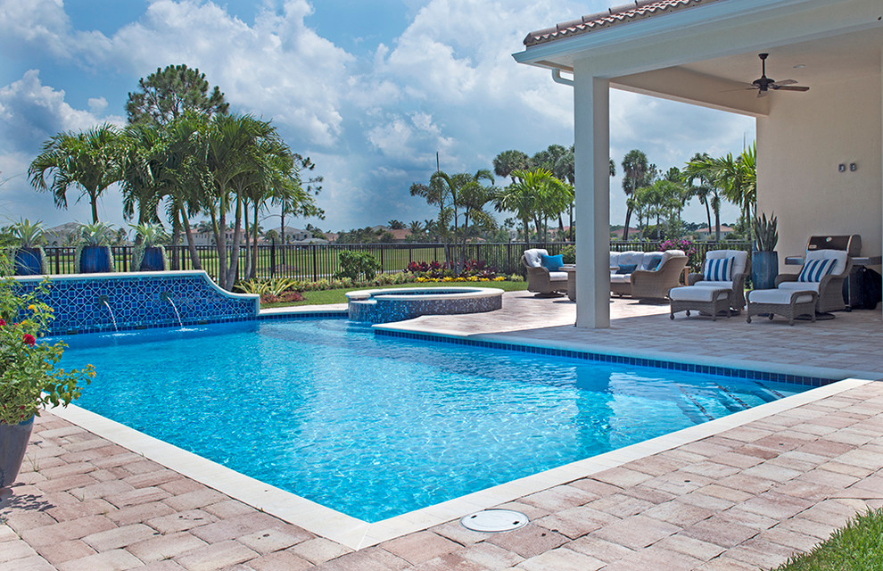 Immagine di una piscina tropicale di medie dimensioni e dietro casa con pavimentazioni in pietra naturale