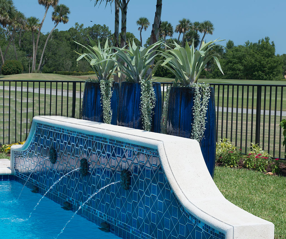 Diseño de piscina tropical pequeña en patio trasero con adoquines de piedra natural