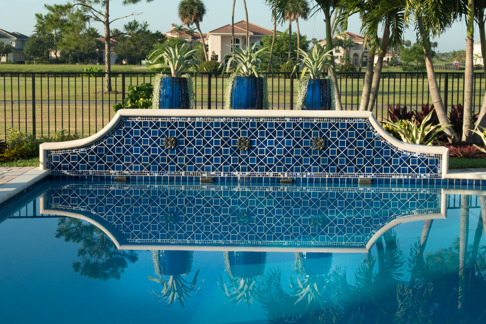 Imagen de piscina tropical grande en patio trasero con adoquines de hormigón