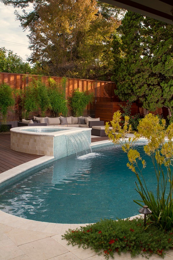 Photo of a medium sized modern back custom shaped swimming pool in San Francisco with a pool house and natural stone paving.