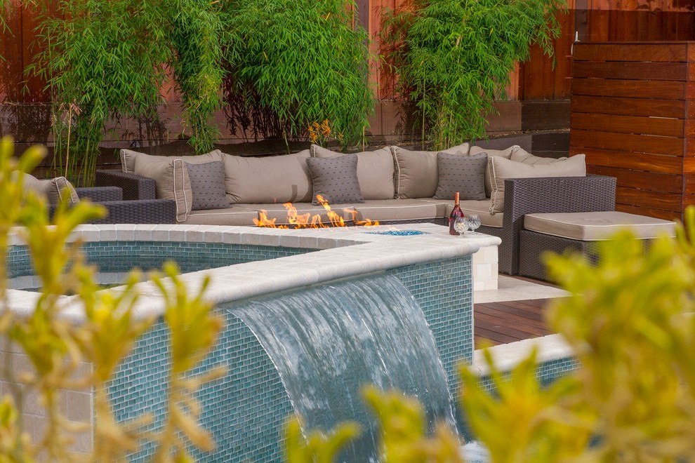 Foto på en mellanstor funkis pool på baksidan av huset, med poolhus och naturstensplattor