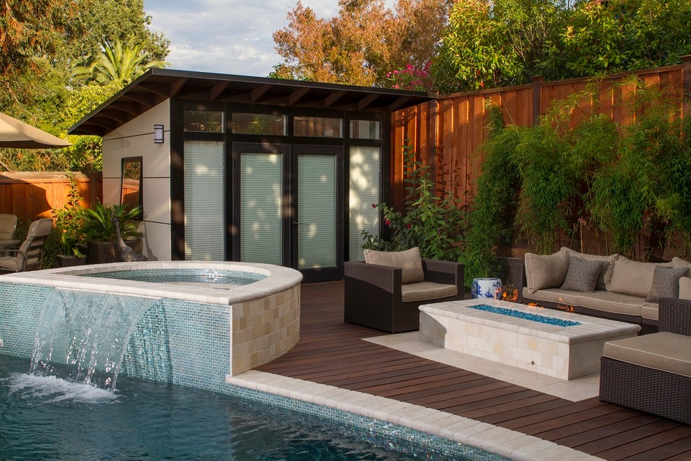 На фото: бассейн среднего размера, произвольной формы на заднем дворе в современном стиле с домиком у бассейна и покрытием из каменной брусчатки с