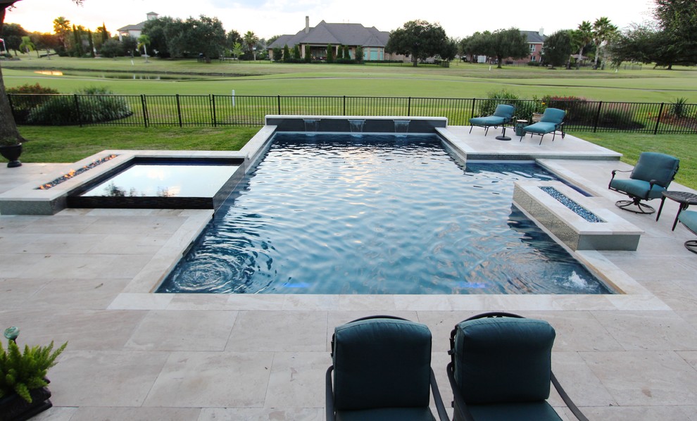 Exemple d'une grande piscine arrière moderne sur mesure avec un bain bouillonnant et des pavés en pierre naturelle.