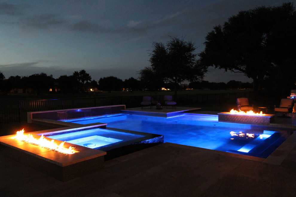 Идея дизайна: большой бассейн произвольной формы на заднем дворе в стиле модернизм с джакузи и покрытием из каменной брусчатки