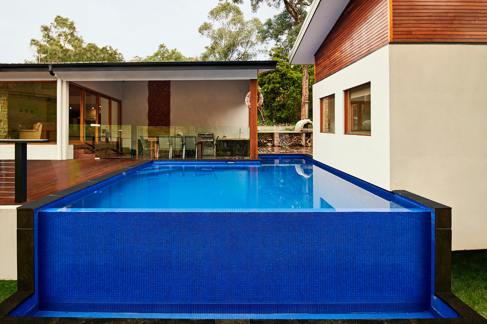Ejemplo de casa de la piscina y piscina infinita de estilo de casa de campo grande a medida en patio trasero con entablado