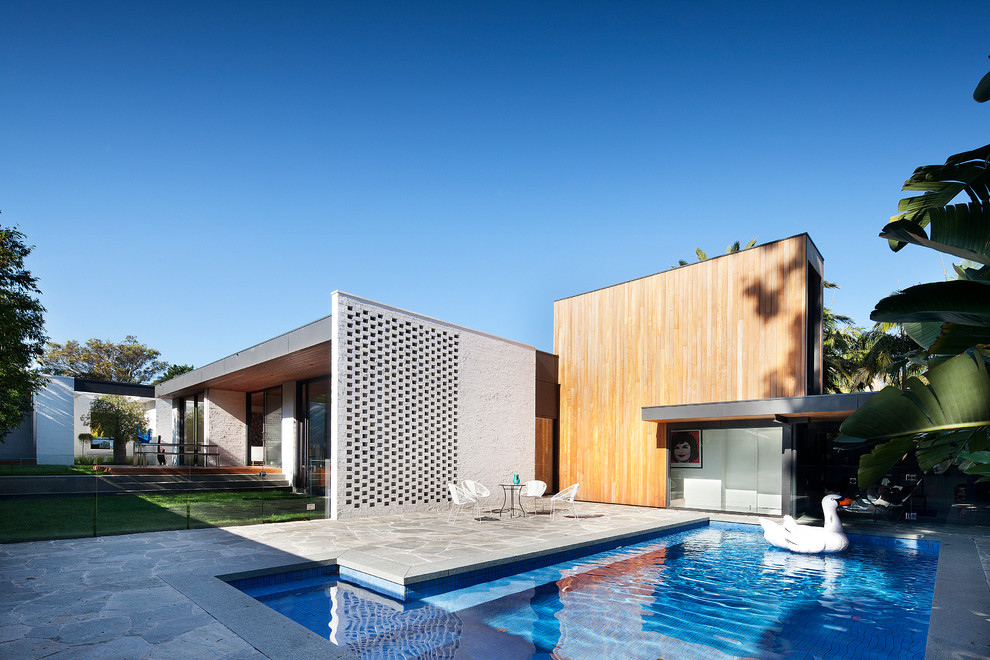 Diseño de piscina actual en forma de L en patio lateral con adoquines de piedra natural