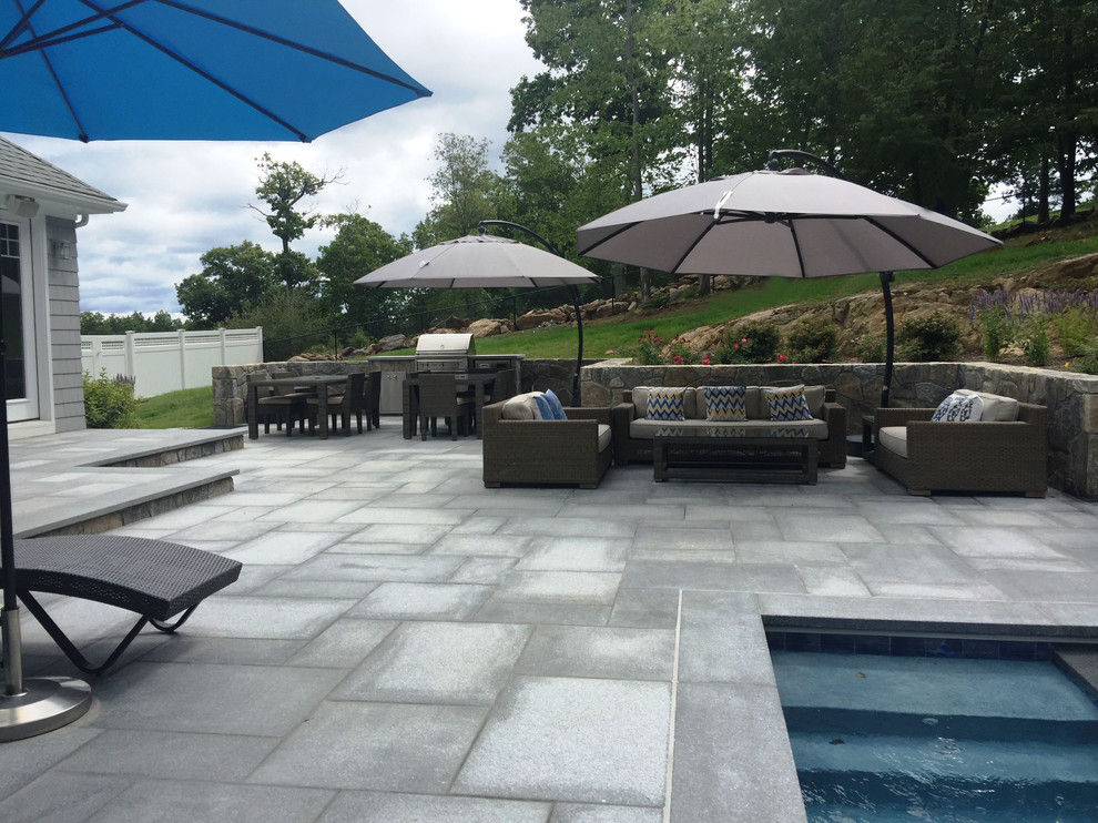 Foto de piscina con fuente actual grande rectangular en patio trasero con adoquines de piedra natural