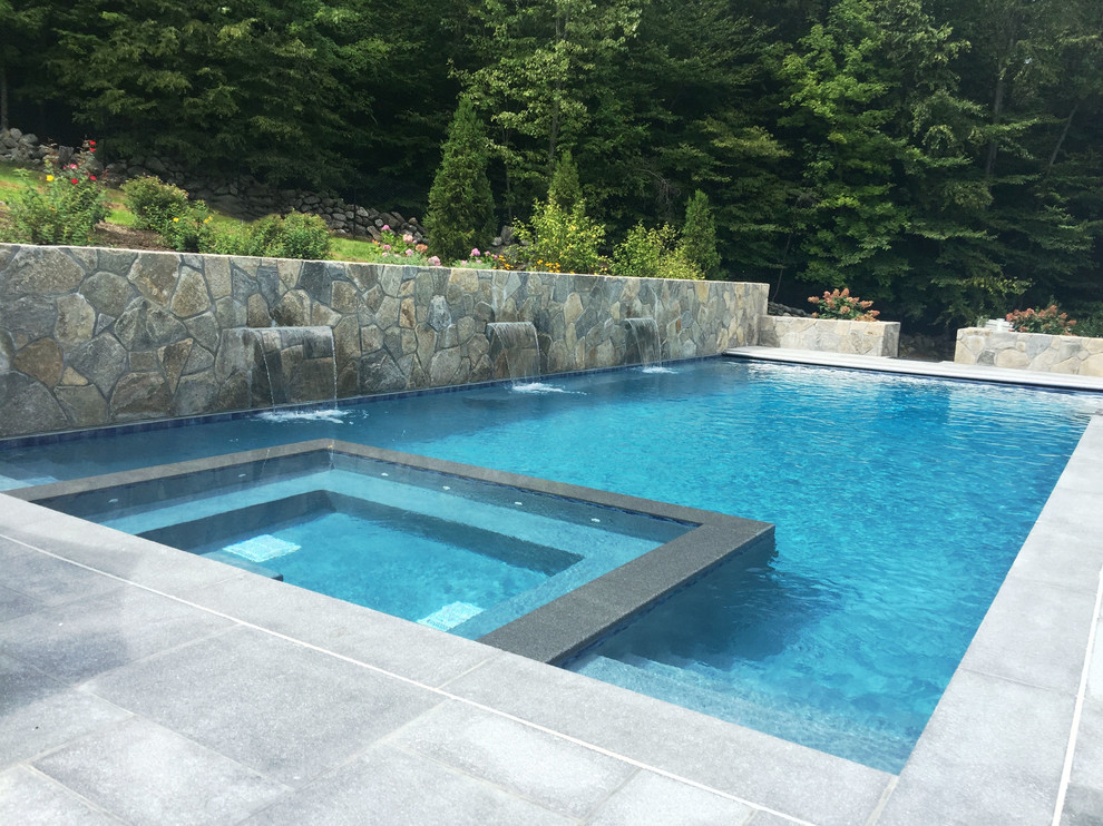 Idee per una grande piscina minimal rettangolare dietro casa con fontane e pavimentazioni in pietra naturale