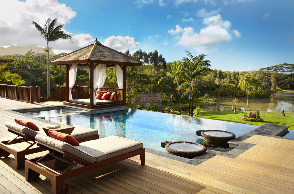Cette image montre une piscine à débordement et arrière ethnique de taille moyenne et rectangle avec une terrasse en bois.