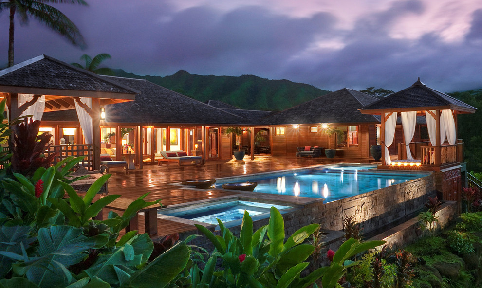Immagine di una piscina a sfioro infinito tropicale rettangolare di medie dimensioni e dietro casa con pedane