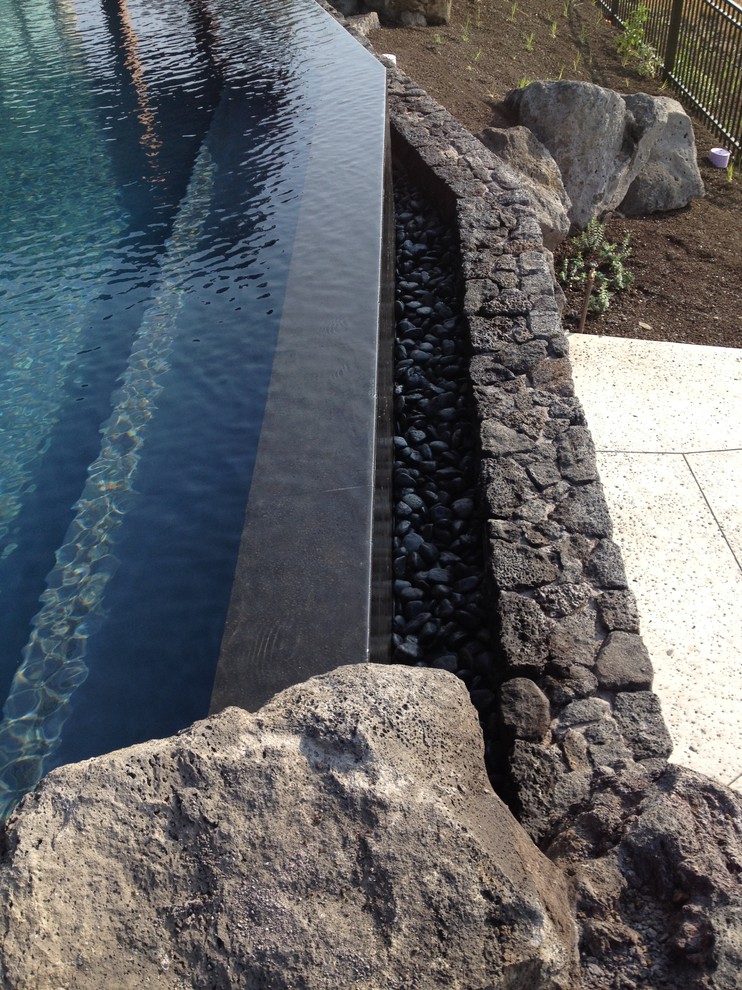 Idee per una piscina a sfioro infinito tropicale personalizzata di medie dimensioni e dietro casa con una dépendance a bordo piscina e pavimentazioni in pietra naturale
