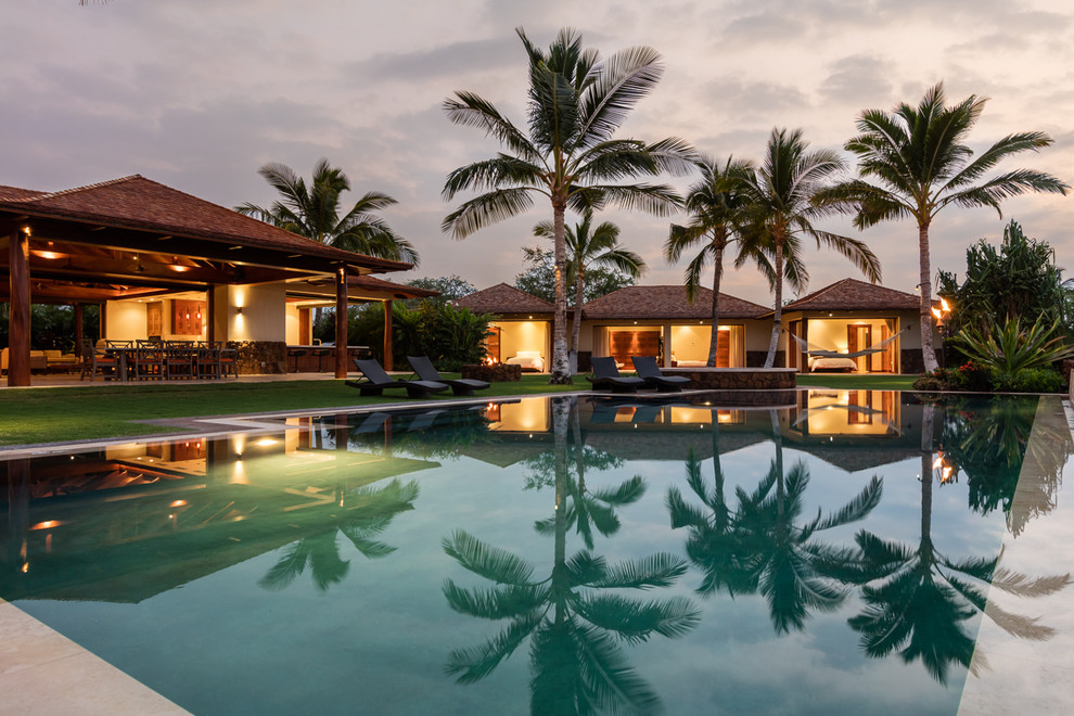 Imagen de piscinas y jacuzzis infinitos tropicales grandes rectangulares en patio trasero con adoquines de hormigón