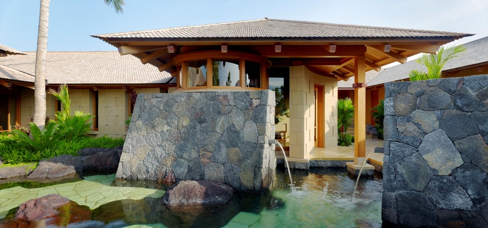 ハワイにあるラグジュアリーなトロピカルスタイルのおしゃれなプール (天然石敷き) の写真