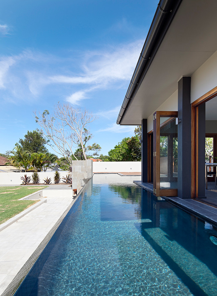 Réalisation d'une piscine design sur mesure avec une terrasse en bois.