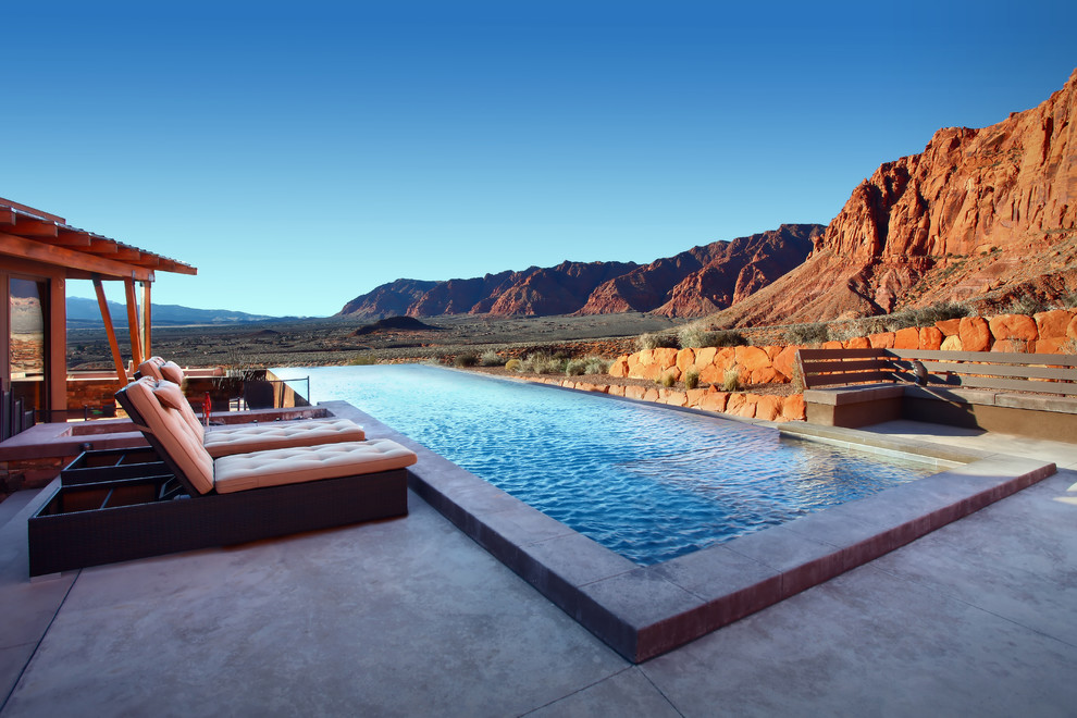 Diseño de piscina alargada de estilo americano de tamaño medio rectangular en patio trasero con losas de hormigón