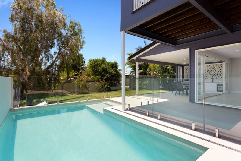 Ejemplo de piscina alargada contemporánea de tamaño medio en forma de L en patio trasero con adoquines de hormigón