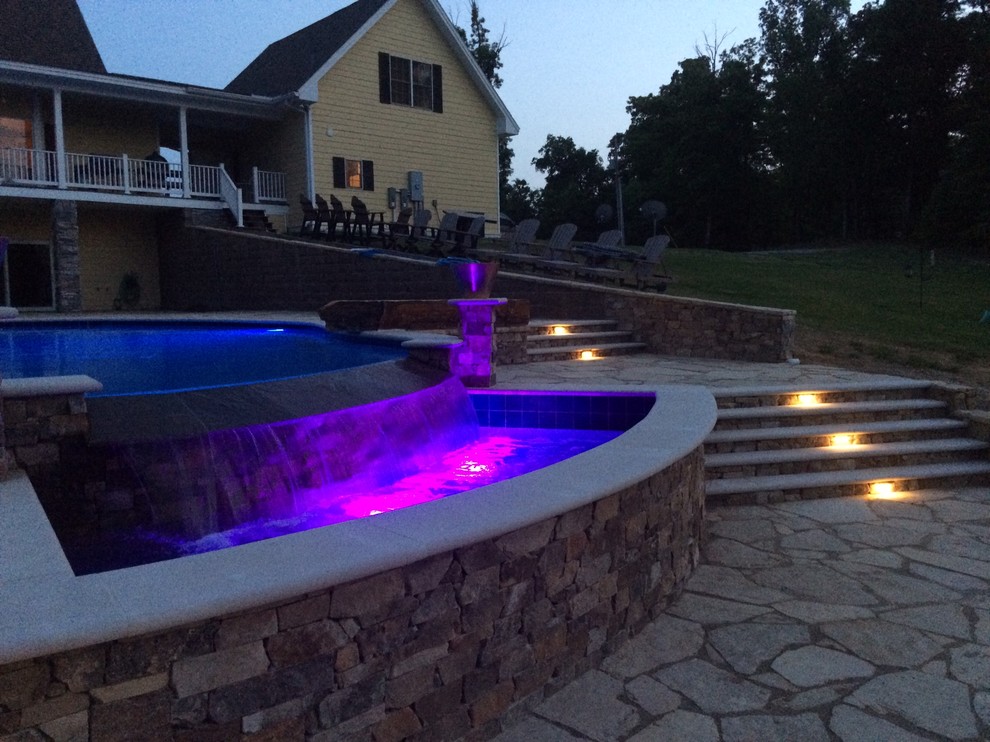 Idee per una grande piscina a sfioro infinito minimal personalizzata dietro casa con pavimentazioni in pietra naturale e una vasca idromassaggio